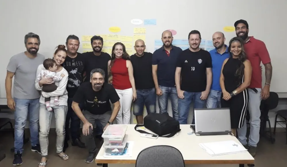 Osmarina com uma turma de empreendedores diante de um painel de post-its